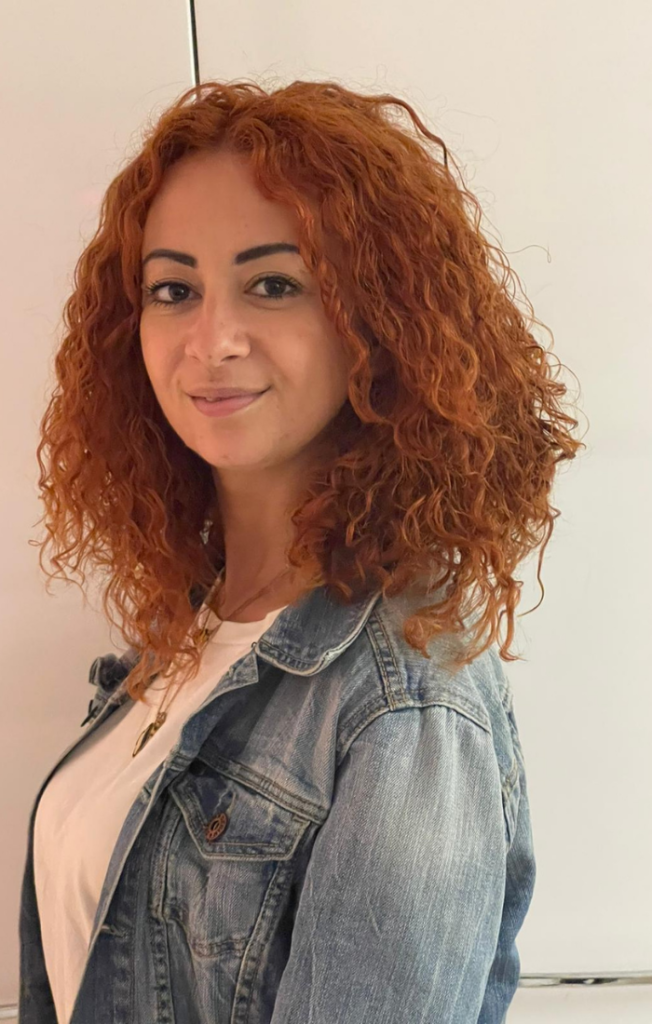 an image of Fiordalina Zammit, she has curly orange hair and is wearing a denim jacket